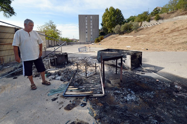 Marseille, 28 septembre 2012, un homme contemple les meubles brûlés dans un campement de Roms, deserté sous la pression des riverains. - AFP / ANNE-CHRISTINE POUJOULAT