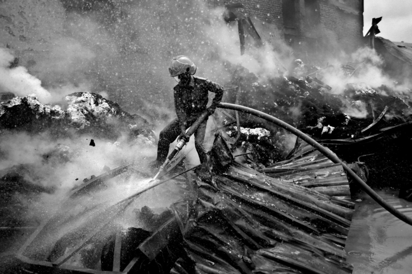 Un pompier tente d'éteindre un incendie à l'usine de Kung Keng. Les conditions de travail dangereuses ont provoqué de nombreux accidents. Zone industrielle, 6 août 2005. 