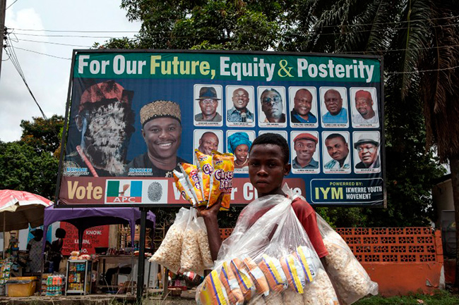 Illustration - Nigeria: Élections à hauts risques le 28 mars - Un vendeur de rue vend du pop-corn devant une affiche électorale défiguré de l'ancien dirigeant militaire nigérian Muhammadu Buhari dans le centre pétrolier de Port Harcourt le 26 Mars 2015. AFP PHOTO / FLORIAN PLAUCHEUR